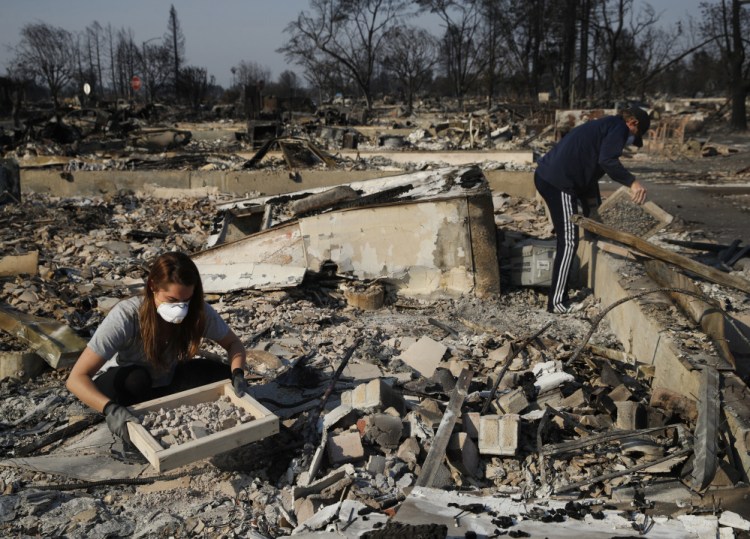 A family works to salvage materials from the rubble of their home, which was destroyed by a wildfire in Santa Rosa, Calif. in October. If House Republicans have their way, victims of hurricanes in Texas and Florida could deduct their losses on their taxes, but California wildfire victims no longer could do so.