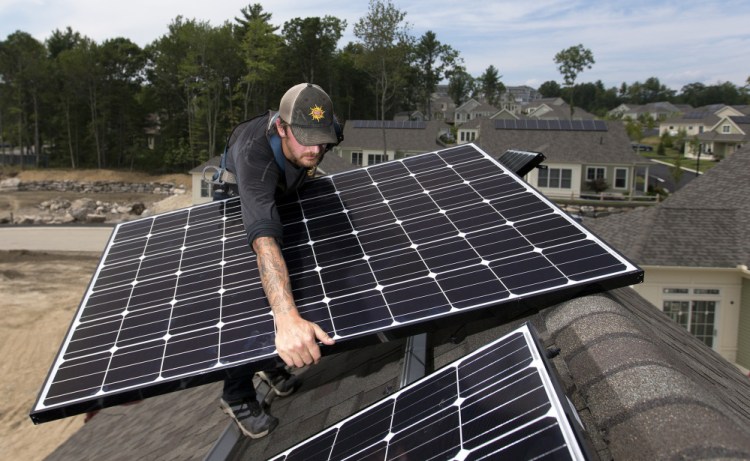 Jack Doherty of ReVision Energy installs a solar panel in Falmouth. Homeowners get a credit for excess energy fed into the grid.