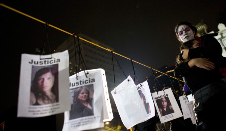 A woman hugs a girl beside images of slain women in Mexico City following a march calling for justice for homicide victims. Of the 52,210 killings of women in Mexico since 1985, nearly a third occurred in the past six years, a report from Mexico's Interior Department said.