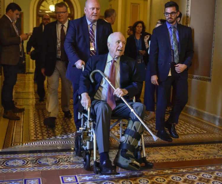 Sen. John McCain, R-Ariz., makes his way to a meeting Dec. 1 in Washington about the Republican tax bill. An Achilles tendon tear in early November put him in a walking boot.