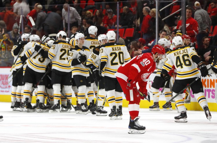 Bruins players celebrate their 3-2 win after Brad Marchand's goal just 35 seconds into overtime Wednesday night in Detroit.