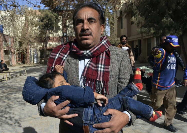 A volunteer rescues a child while others remove a body following the suicide attack on a church in Quetta, Pakistan, on Sunday. One assailant was killed and the other wounded.