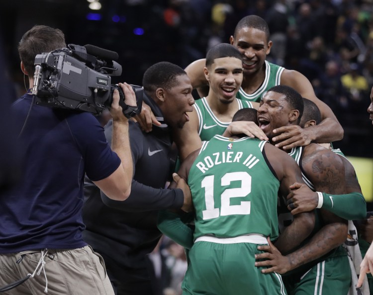 The Celtics' Terry Rozier (12) is mobbed by teammates after his steal and dunk in the finals seconds gave Boston a win over the Indiana Pacers on Monday night in Indianapolis.