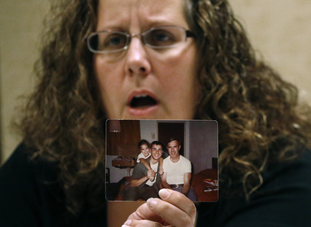 Alexa MacPherson, a victim of clergy sex abuse, holds a photograph of herself as a child as she reacts, Wednesday, Dec. 20, 2017, in Boston, to the death of Cardinal Bernard Law, the disgraced Boston archbishop who epitomized the Catholic Church's failure to protect children from sexually abusive priests. Law died Wednesday in Rome at age 86.  (AP Photo/Bill Sikes)