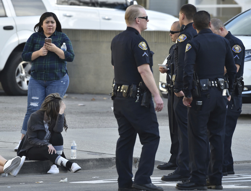 Workers from a nearby business wait by Long Beach, Calif., police Friday after a shooting that left one lawyer dead, another wounded and the shooter dead from a self-inflicted wound.