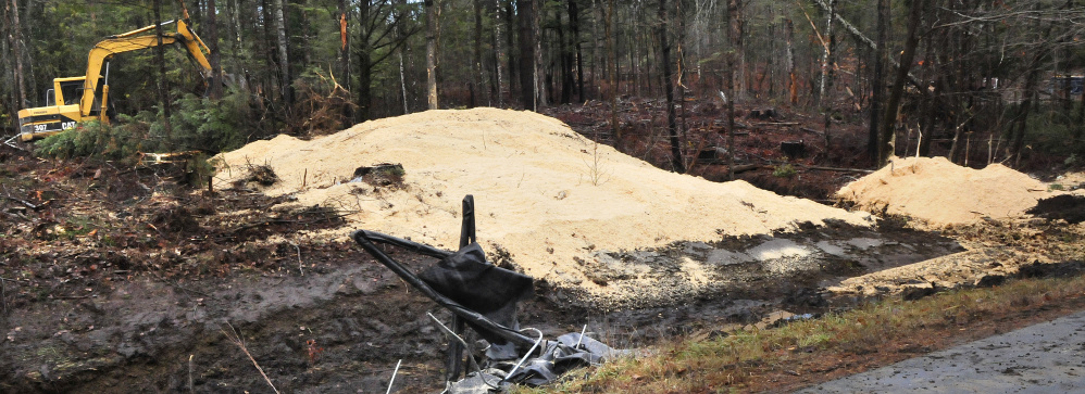 An excavator operator moves sawdust from a ravine after this tractor-trailer overturned early Wednesday morning on Route 150 in Athens.