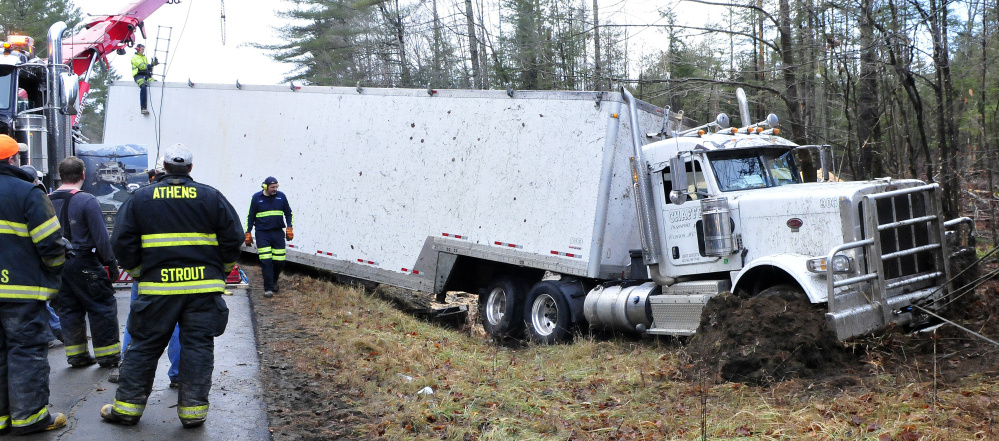 Tow truck operators work on removing this tractor-trailer carrying sawdust that overturned early Wednesday morning on Route 150 in Athens.