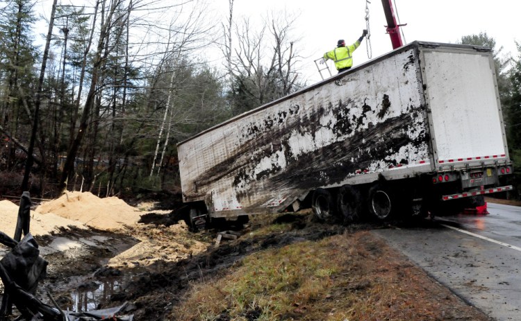 Tow truck operators work on connecting cables to a tractor-trailer carrying sawdust that overturned early Wednesday morning on Route 150 in Athens.