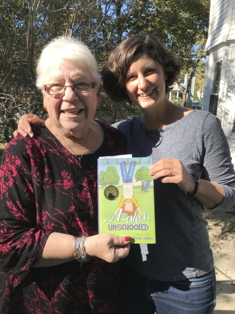 Oxford County Retired Educators Association member and chairperson of this year's Day of Caring Project Karen Ellis, left, receives a book from author Liza Kleinman, of Portland.
