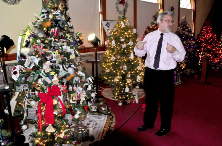 Ken Coville, president of Good Will-Hinckley, talks about the decorated Christmas trees of the many businesses and organizations that sponsored them, including the Recycled Shakespeare Company tree at left, at this year's Festival of Trees. The festival begins Friday in Prescott Hall in Fairfield and runs through Dec. 16.