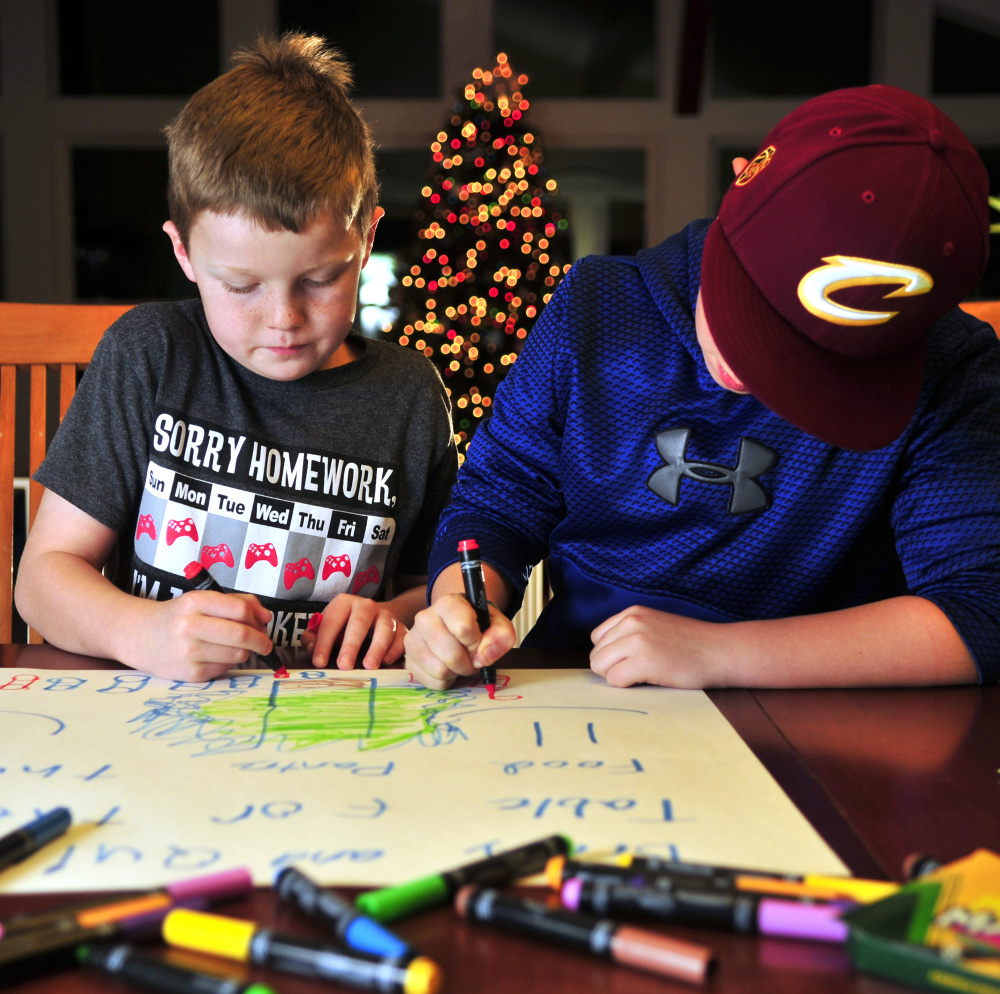 Quincy Emmons, left, and Brady Alexander work on a poster Thursday in Richmond. They plan to staff a table Friday evening at the Richmond tree-lighting to collect nonperishable food for the Richmond Food Bank.