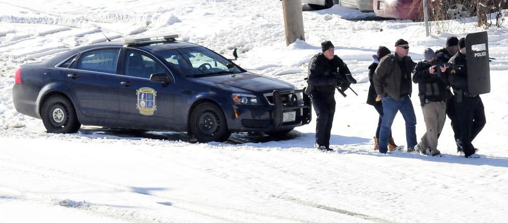 Waterville police and negotiators slowly approach Michael Joslyn at 124 College Ave. in Waterville on Sunday where they shot pepper-balls to subdue Joslyn after a 13-hour standoff at the apartment.