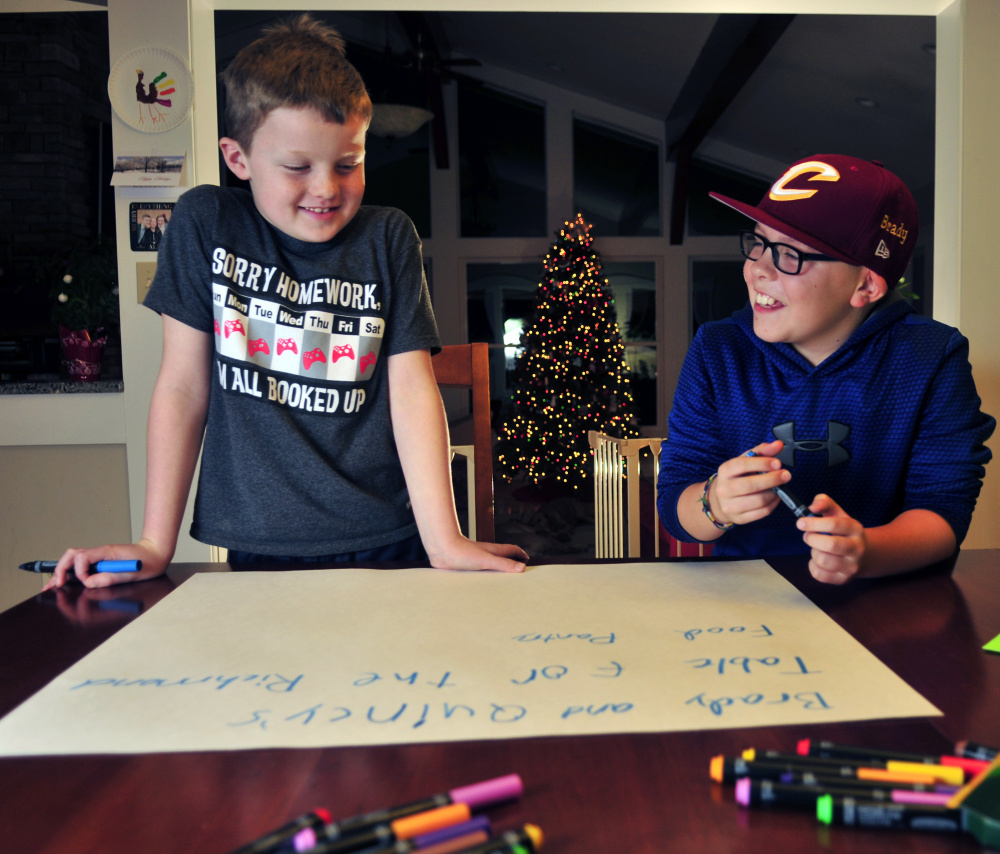 Quincy Emmons, left, and Brady Alexander work on a poster Thursday in Richmond before hosting a food drive at the Richmond tree lighting. Area residents responded, donating 1,280 food items for the cause.
