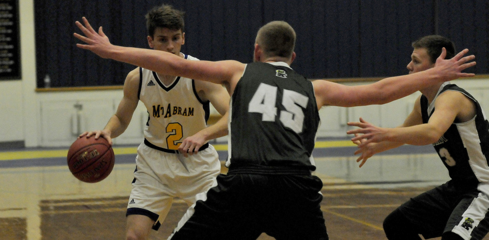 Mt. Abram's Evan MacKay (2) dribbles toward a pair of Winthrop defenders on Monday night in Salem.