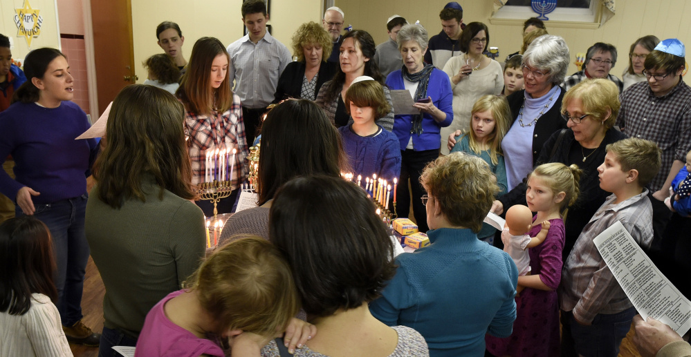 Rabbi Rachel Isaacs, left, leads congregates in songs during the lighting of the menorah during Hanukkah at the Beth Israel Congregation in Waterville on Sunday.