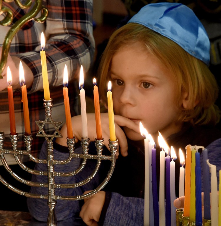 Eben Haviland stares at the burning candles during the lighting of the menorah during Hanukkah at the Beth Israel Congregation in Waterville on Sunday.
