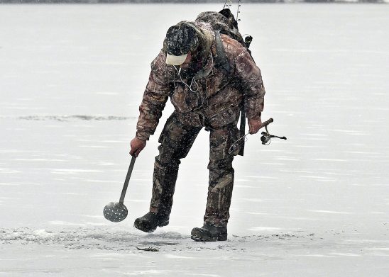 Eric Crowly, of Monmouth, strains ice in a hole Monday on Cochnewagon Lake in Monmouth. The angler caught one brook trout beneath 5 inches of ice along the shoreline.