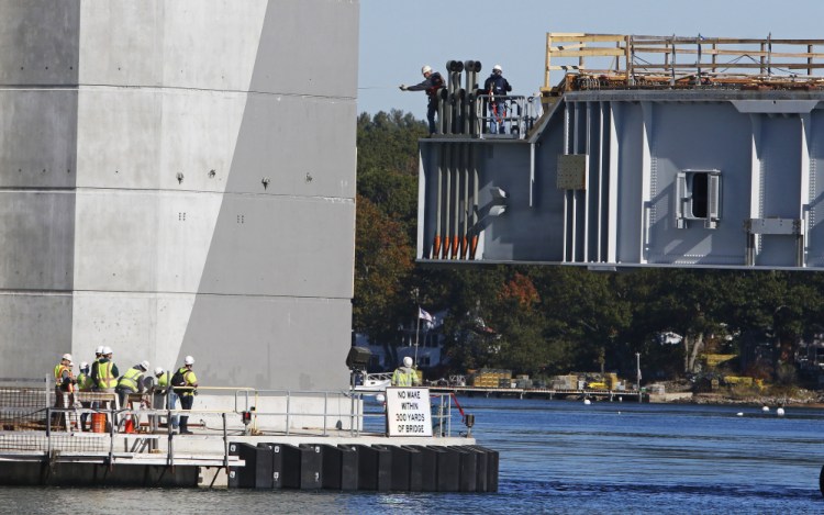 Dana Woods, center, a Cianbro supervisor, measures for clearance from the span back to the bridge tower as the span is positioned on Oct. 18 for connection to the Sarah Mildred Long bridge connecting Kittery to Portsmouth, New Hampshire. Cianbro has announced plans to hire about 300 workers for projects across the state, including improvements to a dry dock at the Portsmouth Naval Shipyard in Kittery.