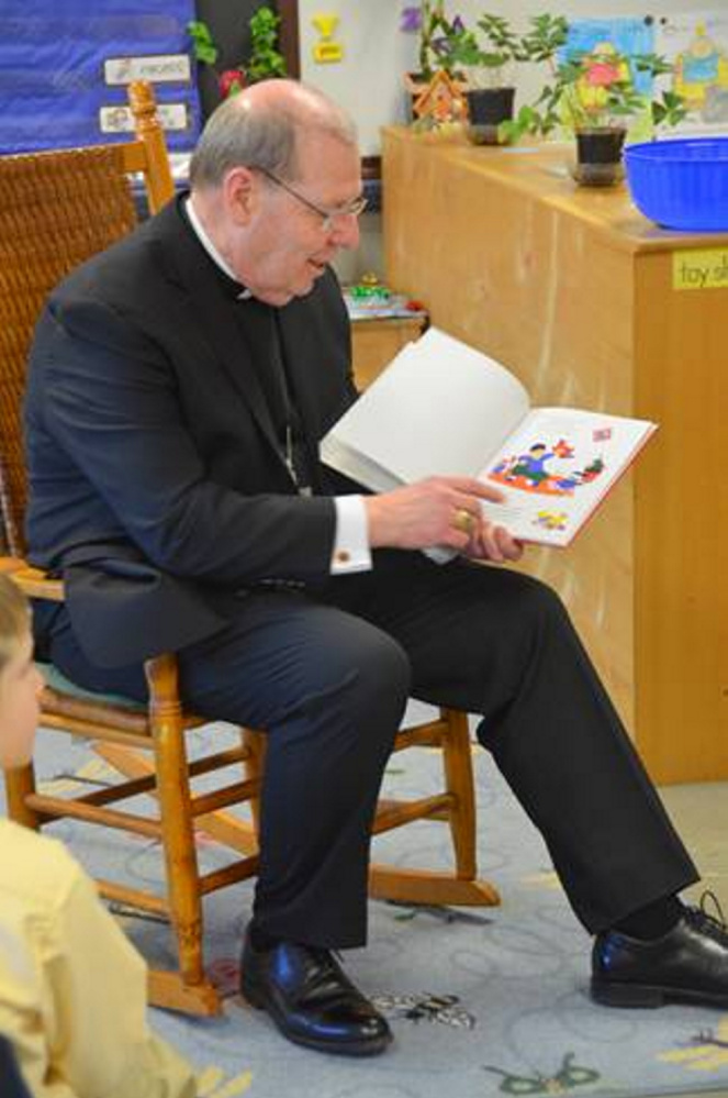 Bishop Robert P. Deeley reads a book to younger students at St. John Regional Catholic Church in Winslow.