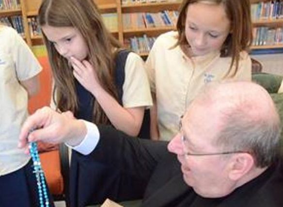 Bishop Robert P. Deeley opens a gift from the third and fourth graders of St. John Regional Catholic Church in Winslow.