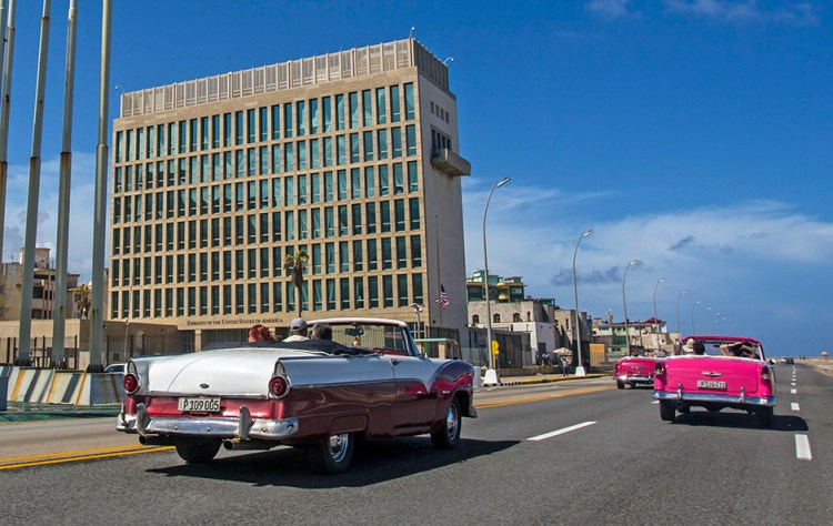 Tourists in vintage American cars pass the American Embassy in Havana in October. The U.S. says 24 embassy  officials and spouses fell ill starting last year in homes and later in some hotels. 
