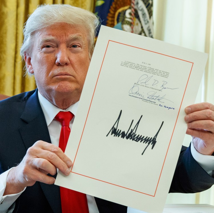 President Trump shows off the tax bill after signing it in the Oval Office on Friday. 