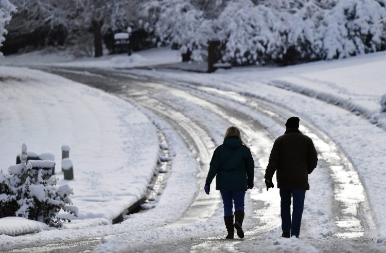  People walk down a snow-covered road after a heavy snow Saturday in Kennesaw, Georgia. The frigid temperatures behind a cold front combined with moisture off the Gulf of Mexico to bring unusual wintry weather to parts of the South. 