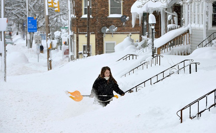 Rochelle Carlotti, 28, shovels steps near her home after a record snowfall on Tuesday,  in Erie, Pa. 