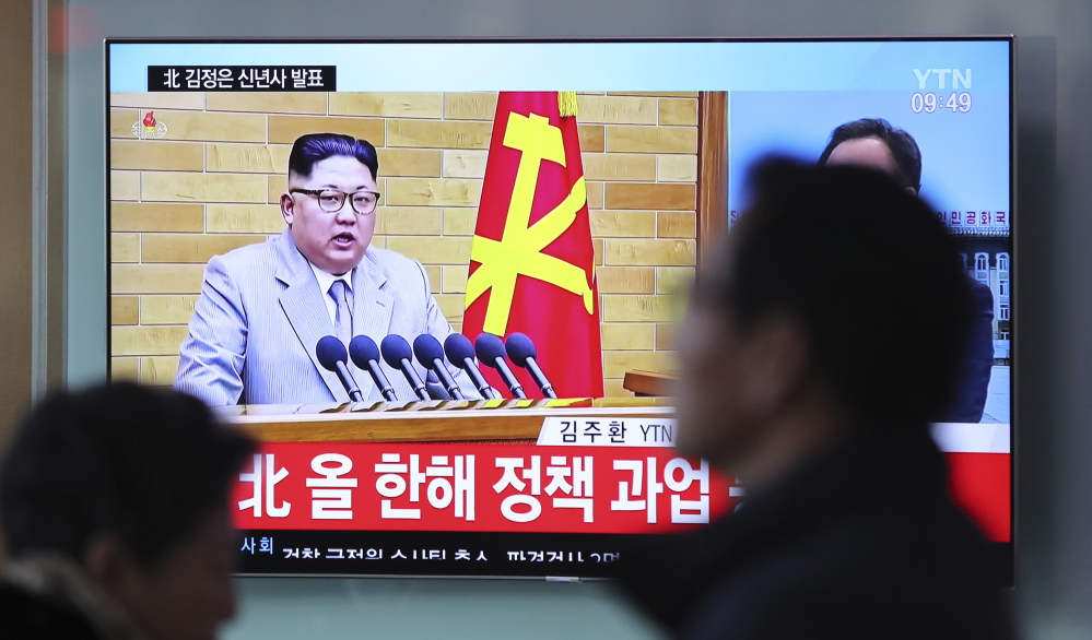 Visitors walk by a TV screen showing a news program reporting about North Korean leader Kim Jong Un's New Year's speech at the Seoul Railway Station in South Korea.