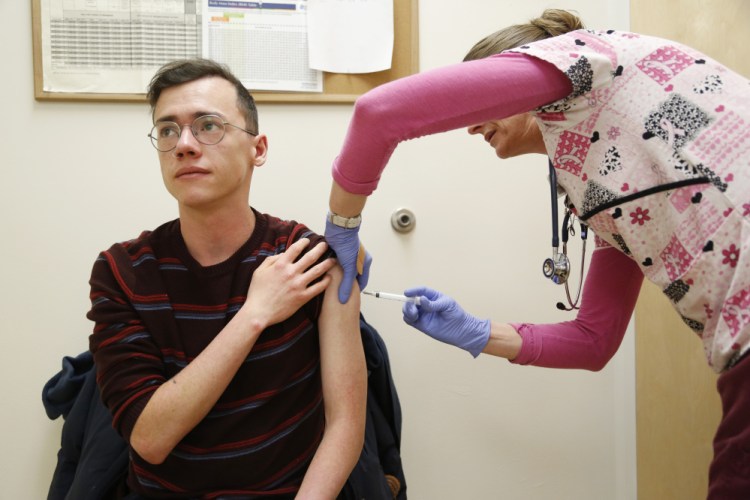 Greater Portland Health medical assistant Anissa Millette prepares to give a flu shot to Troy Ali, 21, of Portland at a clinic Friday.
