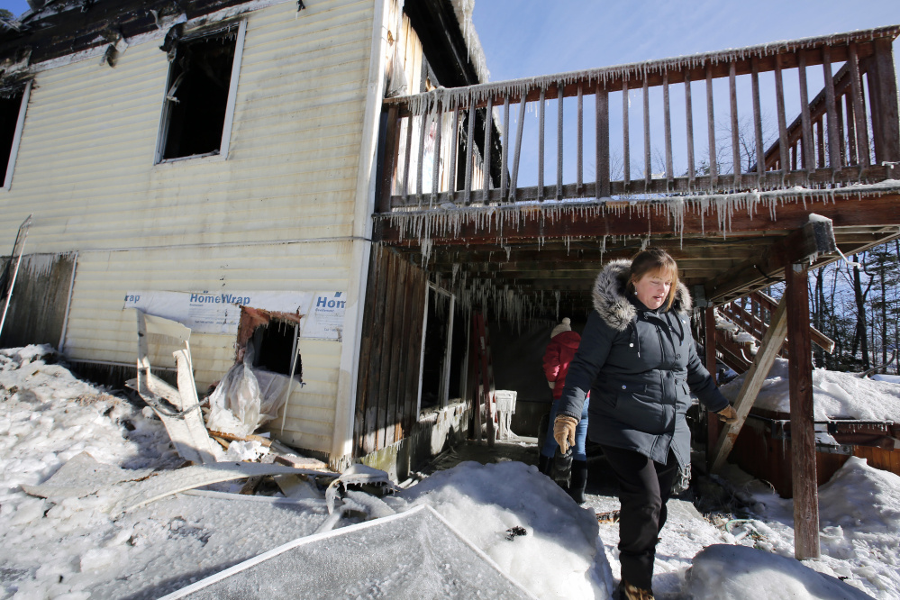 Cherie Eastman emerges from under her deck while surveying her fire-damaged home on Tuesday morning.