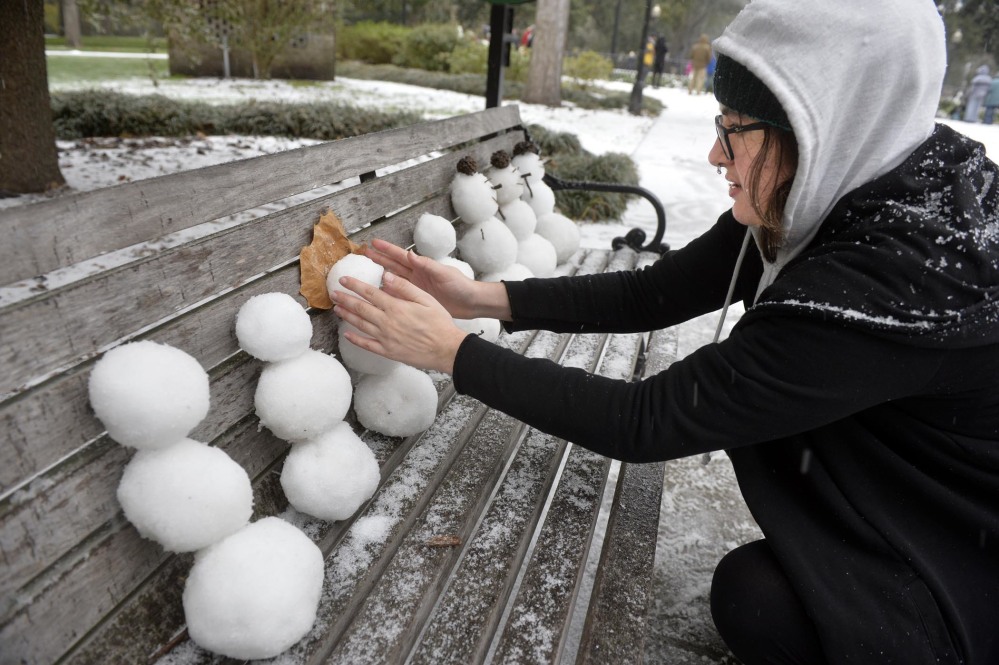Savannah College of Art and Design student Helene Fischer fashions a small snowman on a park bench in Forsyth Park on Wednesday morning in Savannah, Georgia. Fischer, who is from Florida, experienced snow for the first time.