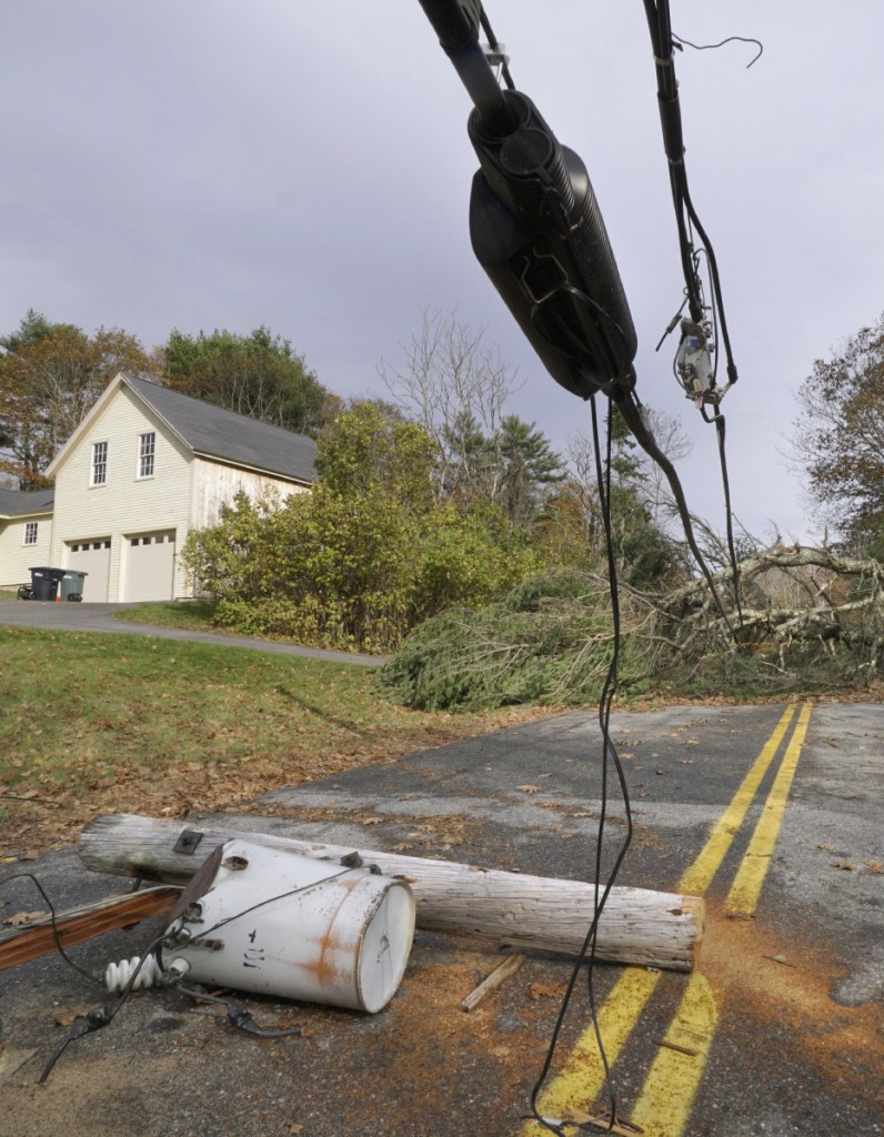 A pole with a transformer attached lies on Flying Point Road in Freeport, under wires weighted down by trees on Nov. 3.