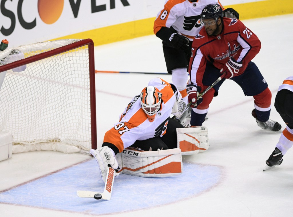Flyers goaltender Brian Elliott reaches for the puck as Devante Smith-Pelly of the Capitals looks for a rebound Sunday during Philadelphia's 2-1 win in overtime.