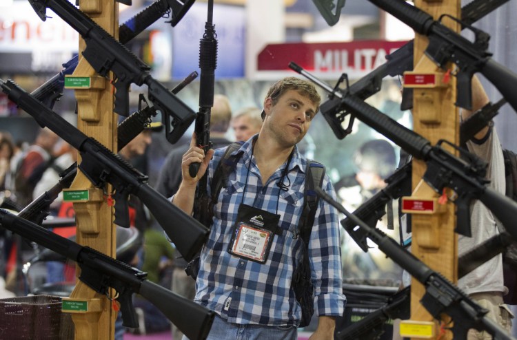 A man inspects rifles at the 2013 SHOT Show in Las Vegas. Mainstream media and the public are barred from this year's show, held near the site of a mass shooting last fall.