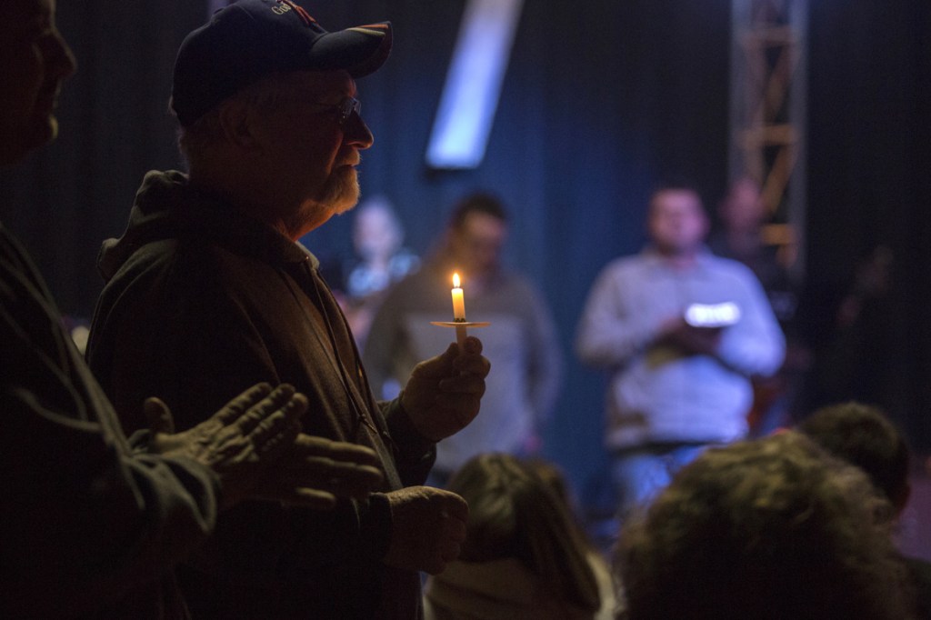 Stan Collins, of Benton, second from left, holds a candle during a vigil at Impact Church in Benton, Kentucky, on Tuesday for victims of the Marshall County High School shooting earlier in the day.