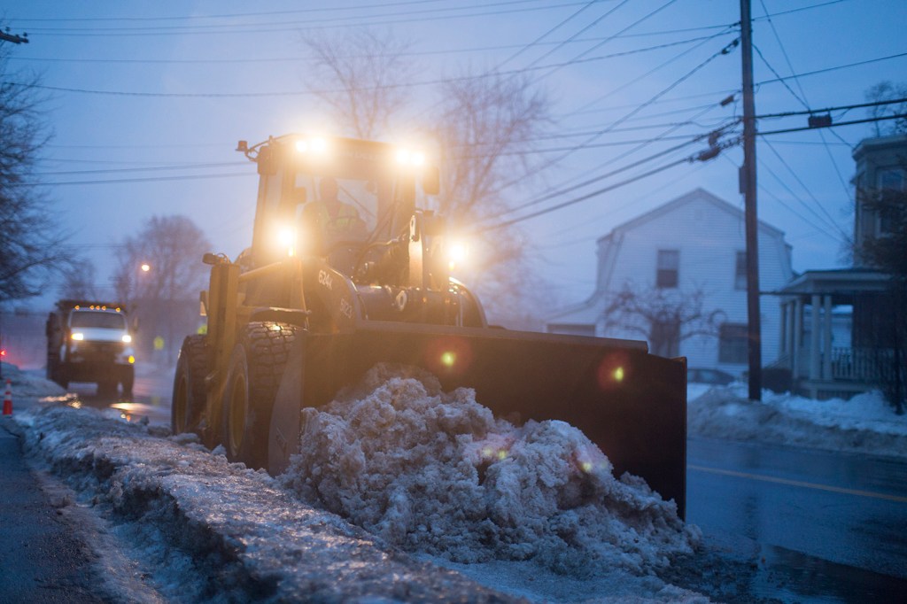 Portland city workers clear softened snow off the side of Presumpscot Street on Friday evening. Crews worked to get snow moved off roadsides, with colder temperatures and a messy winter storm on the way.