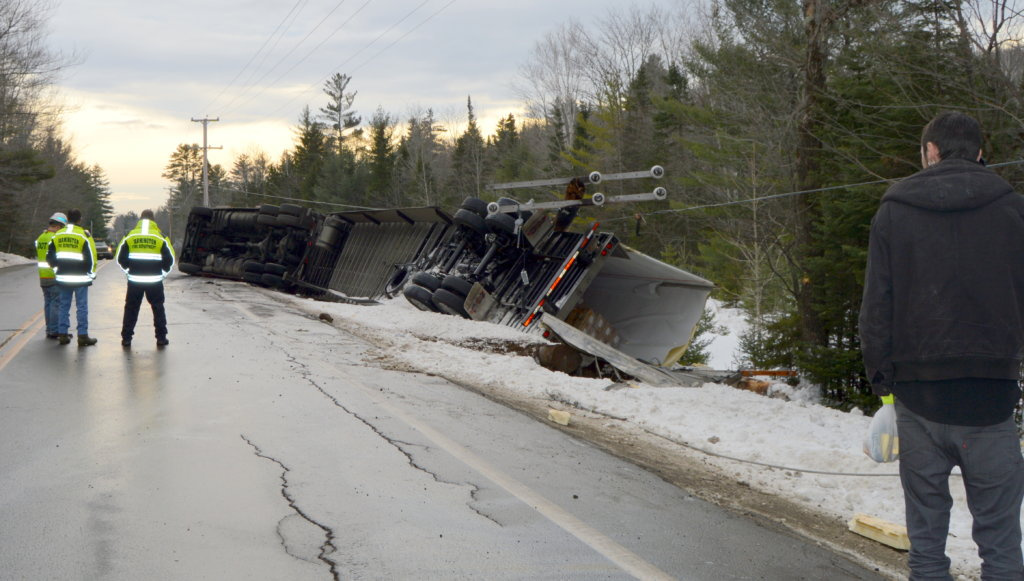 A mangled utility pole and wires lie atop a flipped tractor-trailer Thursday on Route 27 in New Vineyard. The Utah driver was distracted while looking for directions to the Interstate.