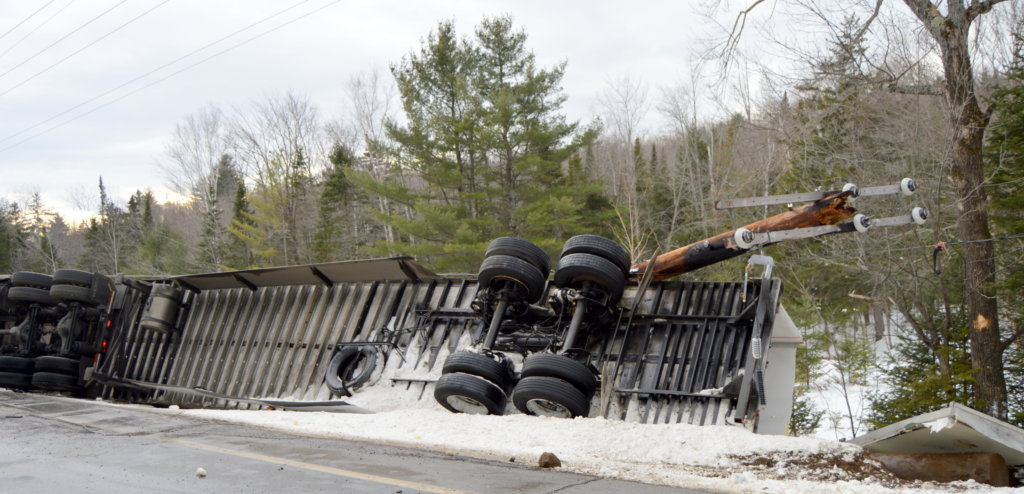 A mangled utility pole and wires lie atop a flipped tractor-trailer Thursday on Route 27 in New Vineyard. The Utah driver was distracted while looking for directions to the Interstate.