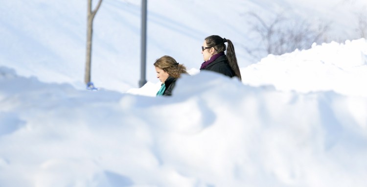 Women walk past snowbanks Wednesday in Gardiner.
