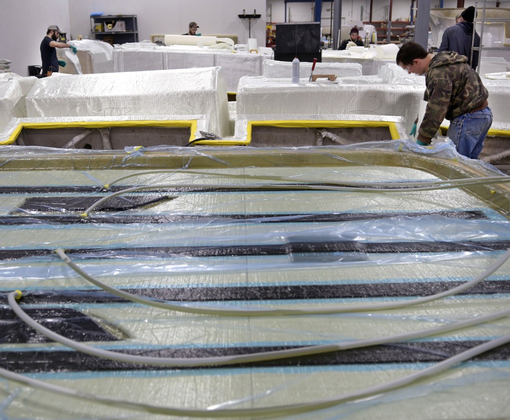 Employees of Southport Boats cut and hang fiberglass on molds Monday as a machine, in the foreground, infuses resin for a hard top at the firm's new location in Gardiner. Formerly part of Augusta's Kenway Corp., Southport has relocated to Gardiner under new ownership and will continue to produce its line of powerboats there.