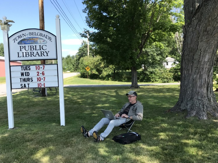 Robin Budd, a tourist visiting from Toronto, Ontario, finds a shady spot under a tree Aug. 9, 2017, at the Belgrade Public Library on Depot Road. Town voters will decide at the upcoming Town Meeting whether the library should have a full-time director.