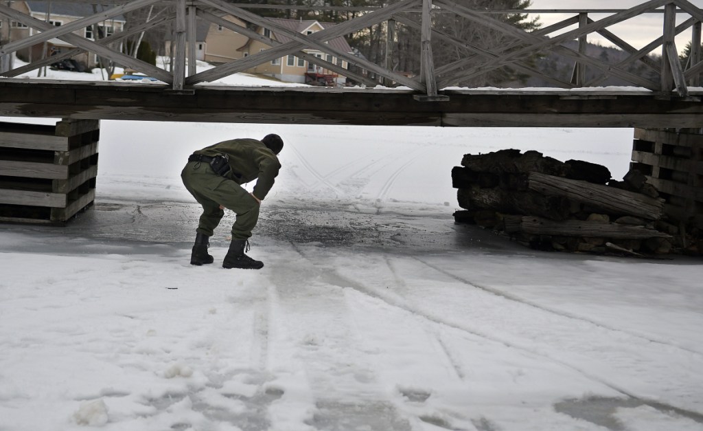 District Game Warden Robert Decker on Sunday inspects a pier a snowmobile struck on a wooden bridge on Togus Pond in Augusta. Wardens are investigating the accident that seriously injured the 52-year-old male operator.