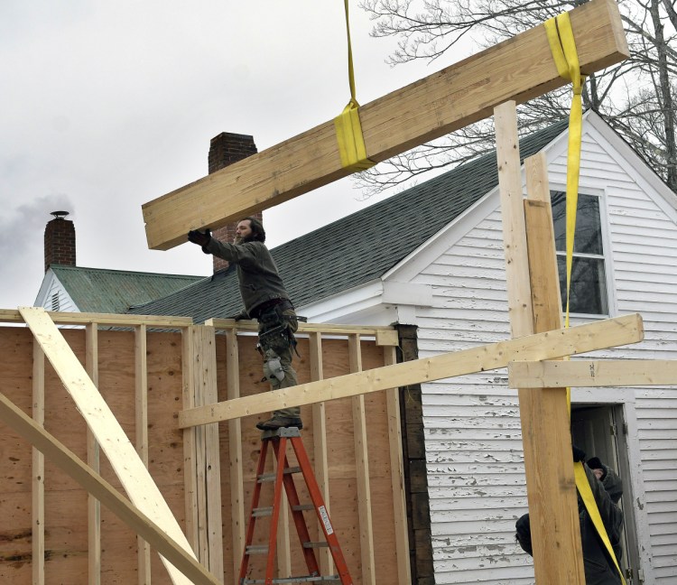 Workers set a roof beam on Monday for the expansion of the Dr. Shaw Memorial Library in Mount Vernon.