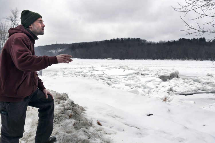Nate Taczli surveys ice on the Kennebec River on Monday behind the Hallowell firm he manages, S. Masciadri & Sons. Forecasts call for rain and warmer temperatures on Tuesday, increasing the risks of flooding. The monument business has carved monuments and headstones at the same spot since 1918.