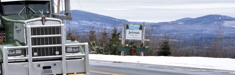 Trucks pass the Jackman town line sign on Monday, framed by mountains on U.S. 201.