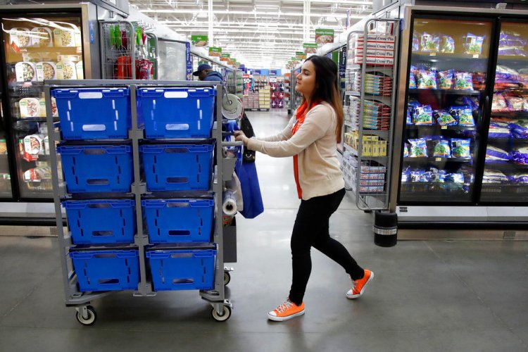 Laila Ummelaila, a personal shopper at the Walmart store in Old Bridge, N.J., pushes a cart with bins as she shops for online shoppers, in November. On Thursday, Walmart announced it is boosting its starting salary for U.S. workers to $11 an hour.