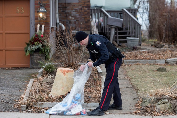A police officer investigates outside a house on Mallory Crescent in Toronto, where Bruce McArthur did landscape work, on Monday. McArthur, 66, was charged Jan. 18 in the presumed deaths of Selim Esen and Andrew Kinsman. He was further charged on Monday in the deaths of Majeed Kayhan, 58, Soroush Mahmudi, 50, and Dean Lisowick, 47. 