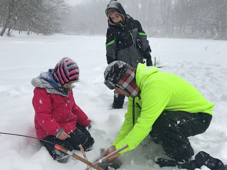 Keith Stinson of South Portland checks ice fishing lines with his 7-year-old daughter, Jordyn, left, and son Devin, 9, at Hinckley Park Thursday. Unfortunately, the fish slipped the line. 
