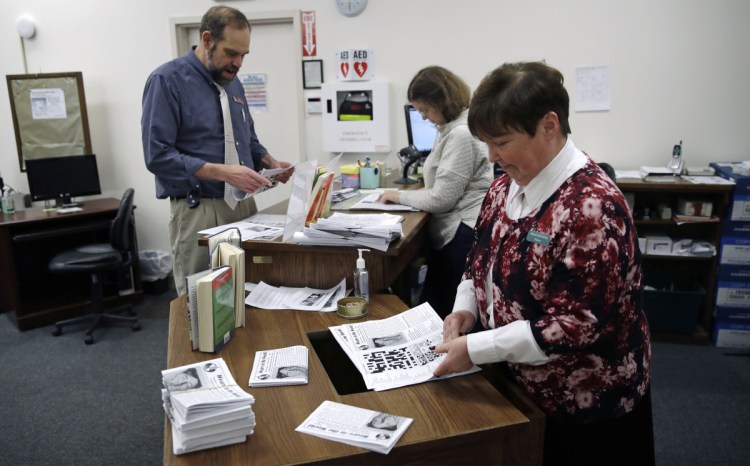 Librarian Thelma Tracy, right, folds editions of the Weare in the World with her co-workers at the public library in Weare, New Hampshire, last month.